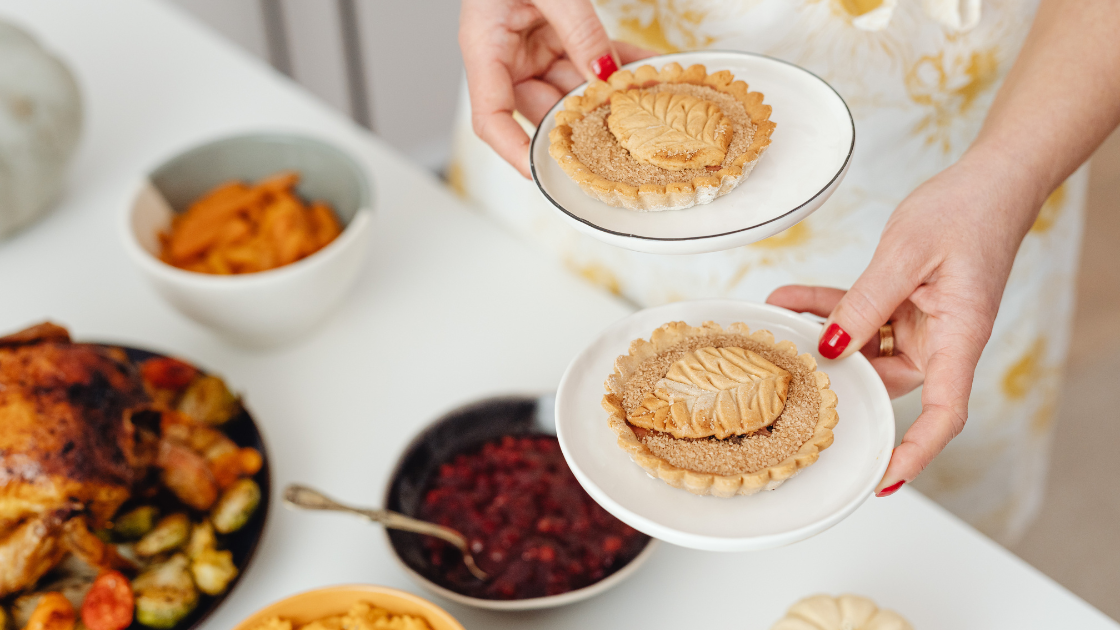 two hands holding small pastries over a plate of festive dishes